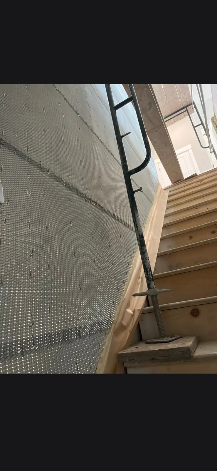 Interior walls lathed and meshed beside a stairwell, ready for stucco base coat