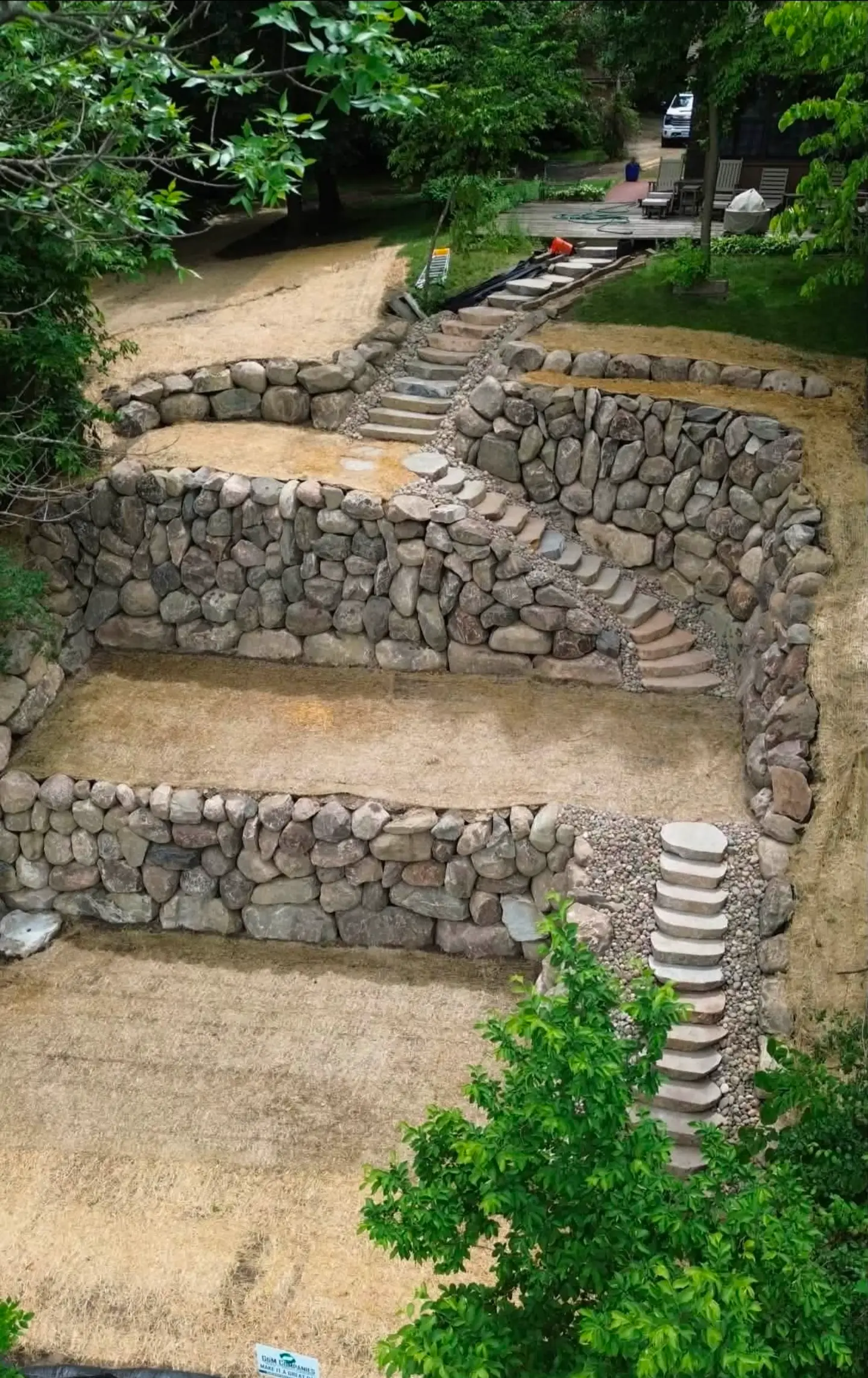 Terraced boulder retaining wall with stone steps on a sloped lot